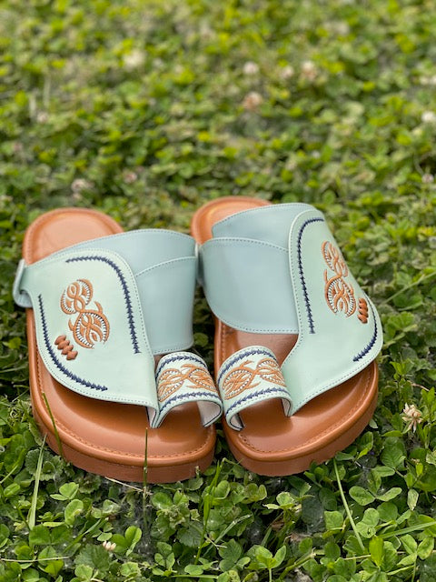 “Heritage Sandal in mint green leather featuring beautifully embroidered orange and navy blue stitching